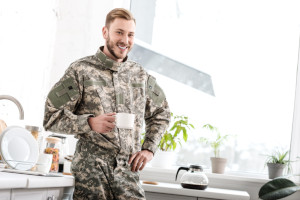 army soldier holding coffee cup in kitchen smiling