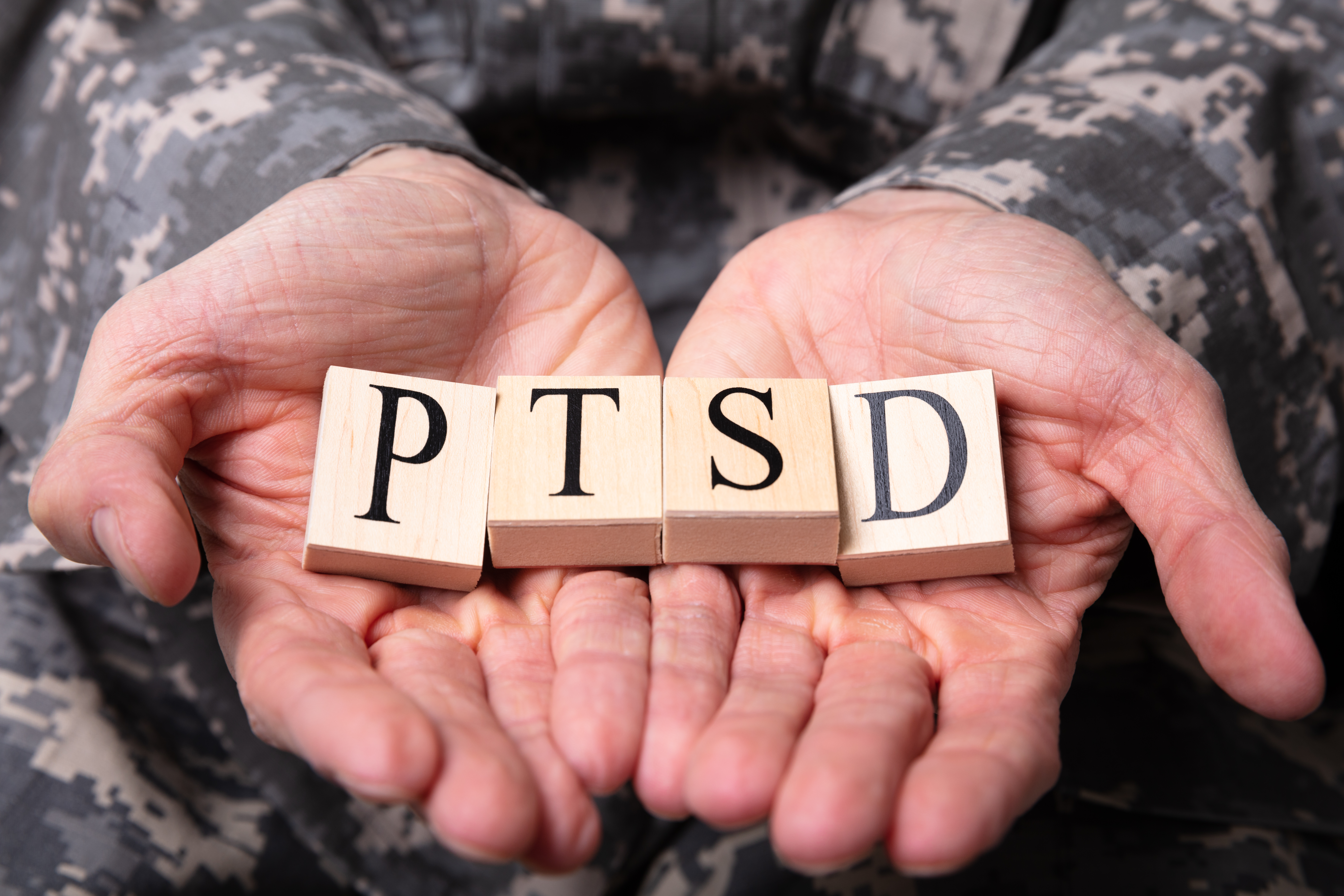 Male Soldier Holding Wooden Cubes With PTSD Text
