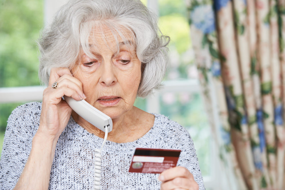 elderly lady giving credit card details over phone, life insurance scam